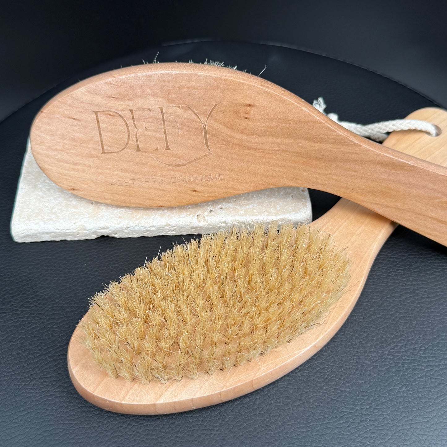 Wooden brush with bristles and a white scrubber on a dark surface