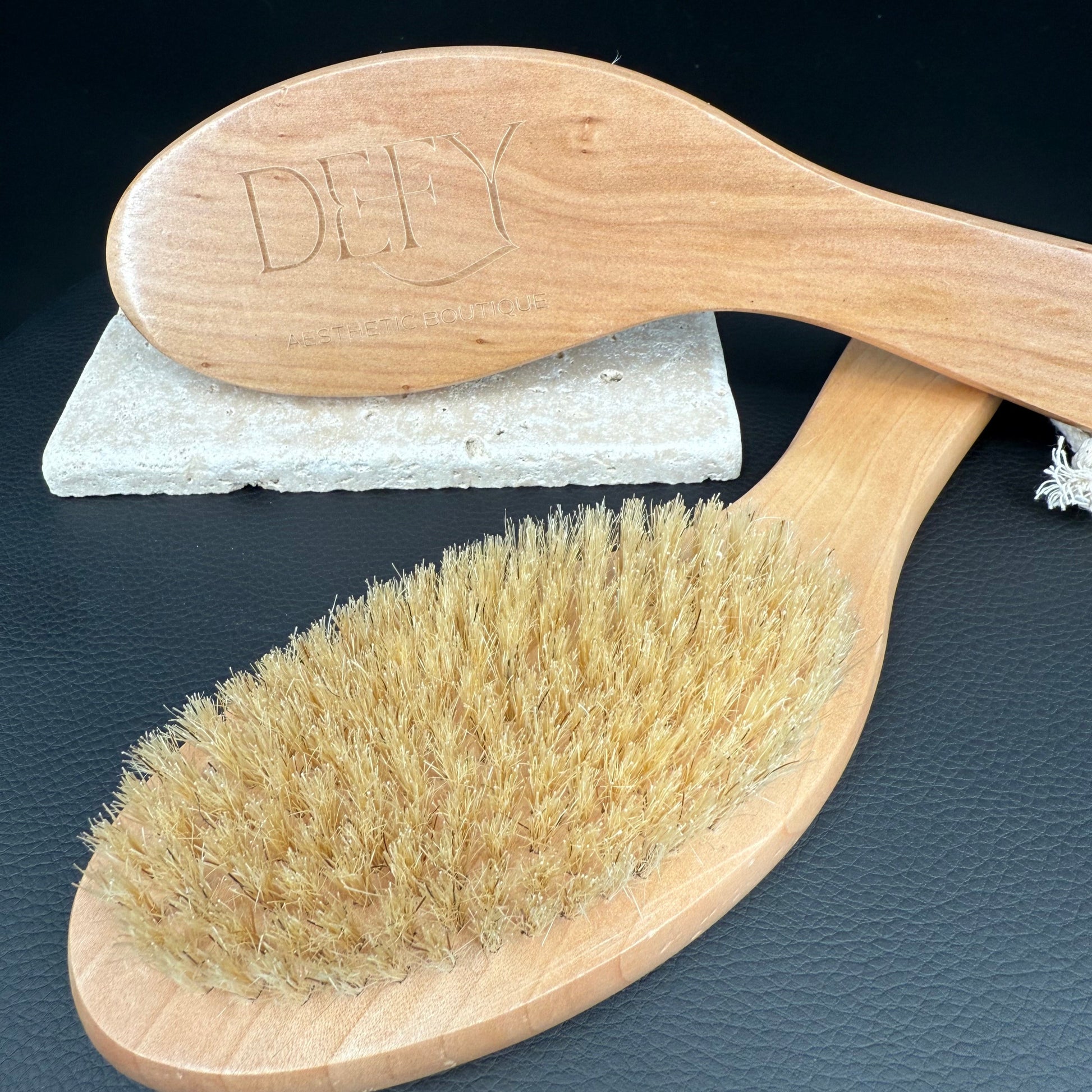 Wooden brush with bristles and a white scrubber on a dark surface