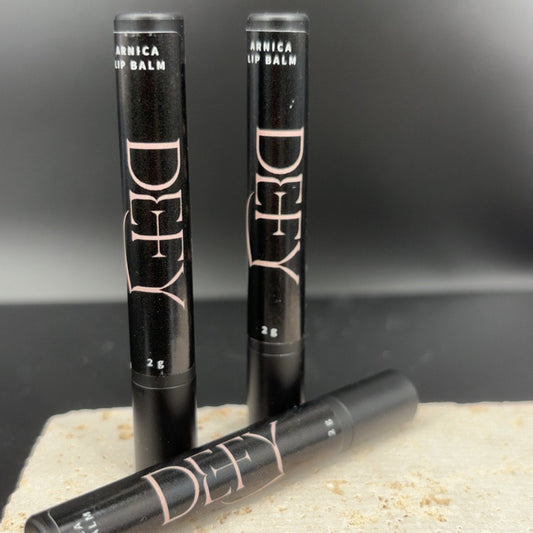 Three lip balms with visible branding on a stone surface and dark background